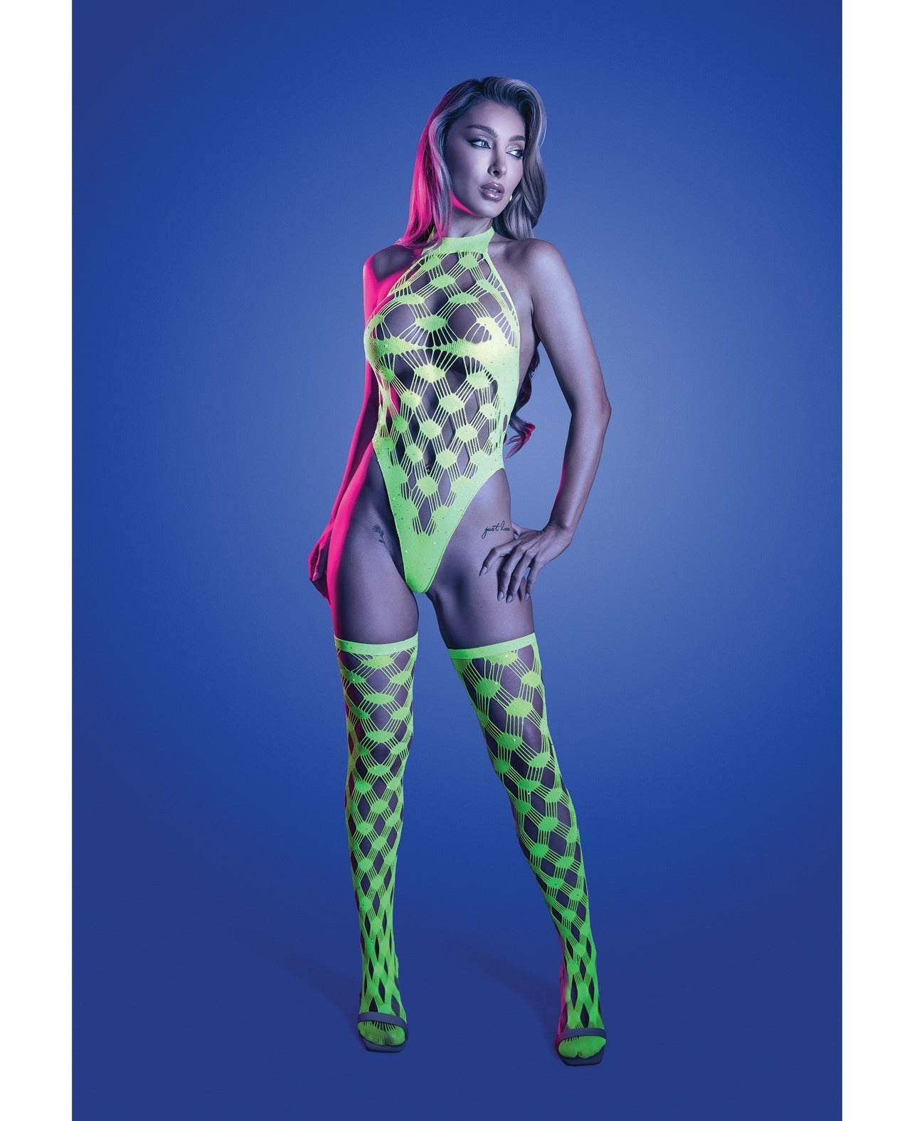 A model poses in a neon green bodysuit with matching fishnet thigh-high stockings against a blue studio background.