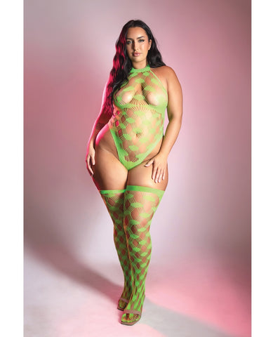 A woman modeling a bright neon green fishnet bodysuit and matching thigh-high stockings with a green geometric pattern, set against a pink studio backdrop.