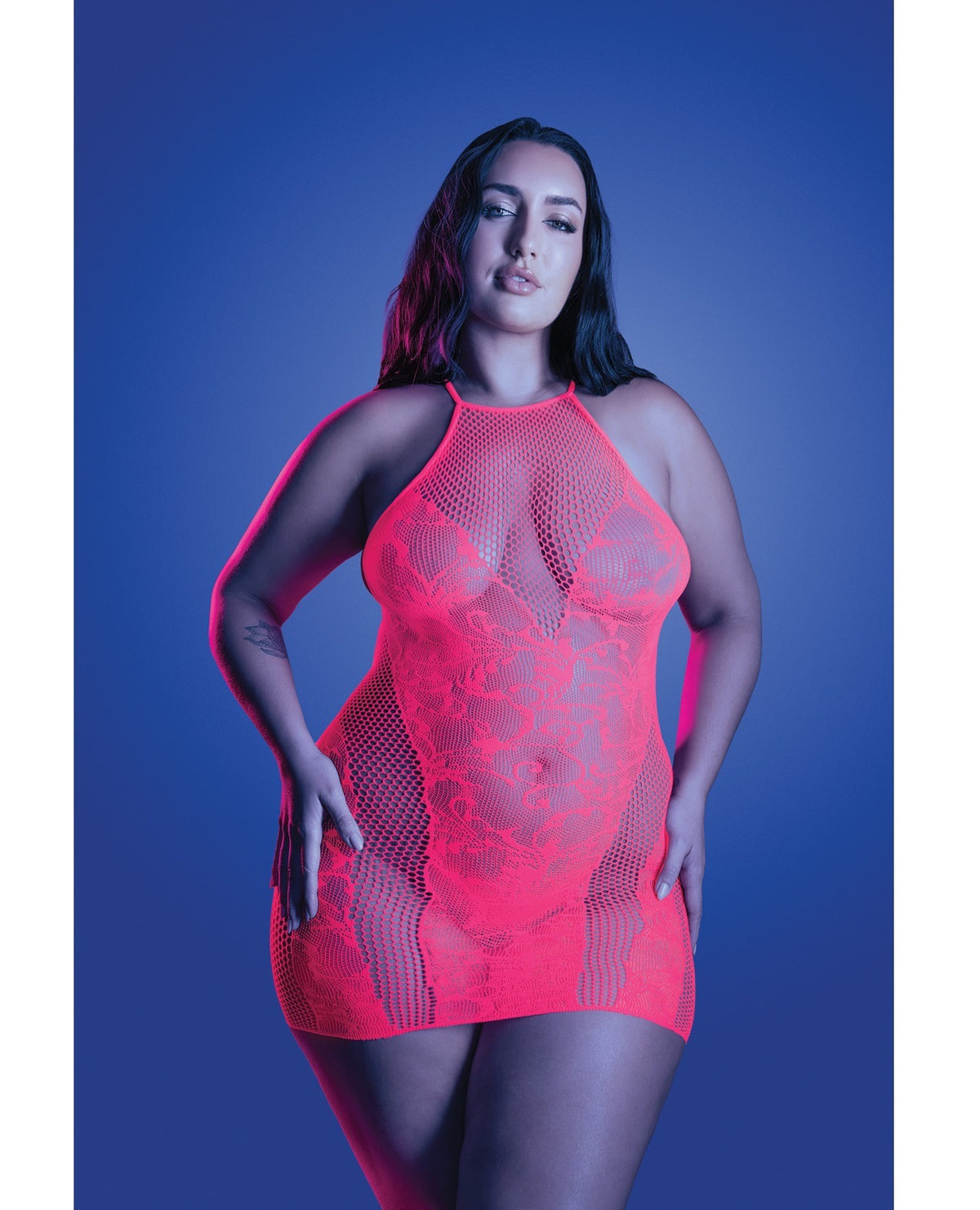 A woman modeling a bright neon pink fishnet halter bodysuit against a blue studio background.