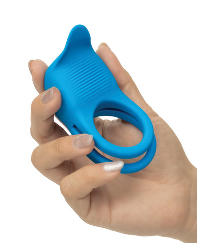 A bright blue silicone cock ring with a textured front and curved top, shown being held in a person's hand against a plain white background.