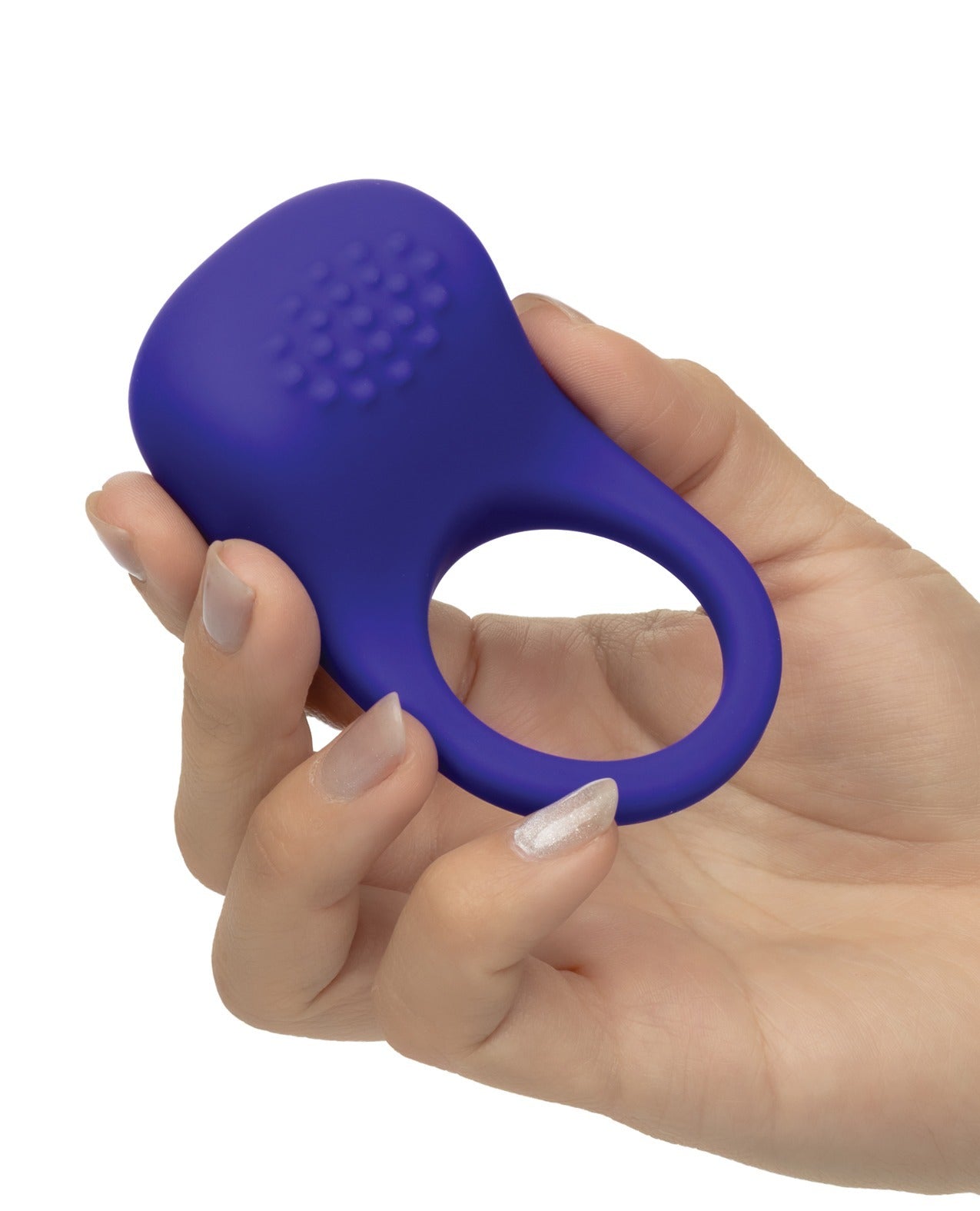 A hand holding a small, oval-shaped purple silicone cock ring with a textured top and a ring-shaped opening, shown against a plain white background.