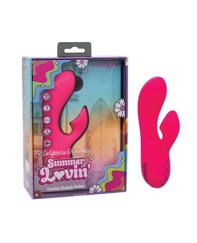 A bright pink curved personal massager shown next to its retail packaging box. The box features retro-style graphics with the text 'California Dreamin' Summer Lovin'' and 'Venice Beach Babe'.