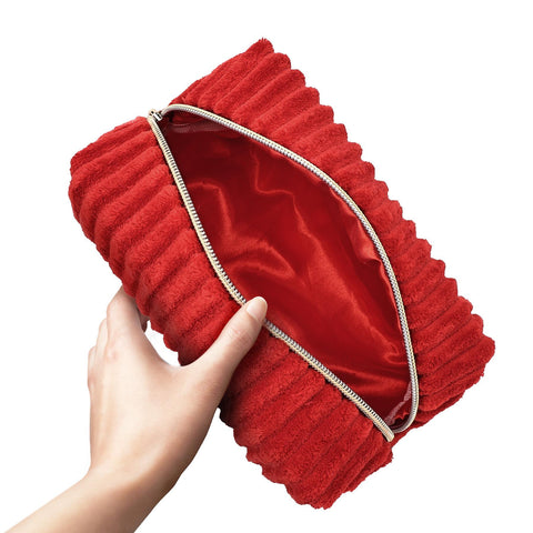 Red pleated bag held by a hand on a white background
