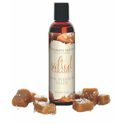 A bottle of Intimate Earth Salted Caramel Natural Flavor Glide with caramels around it