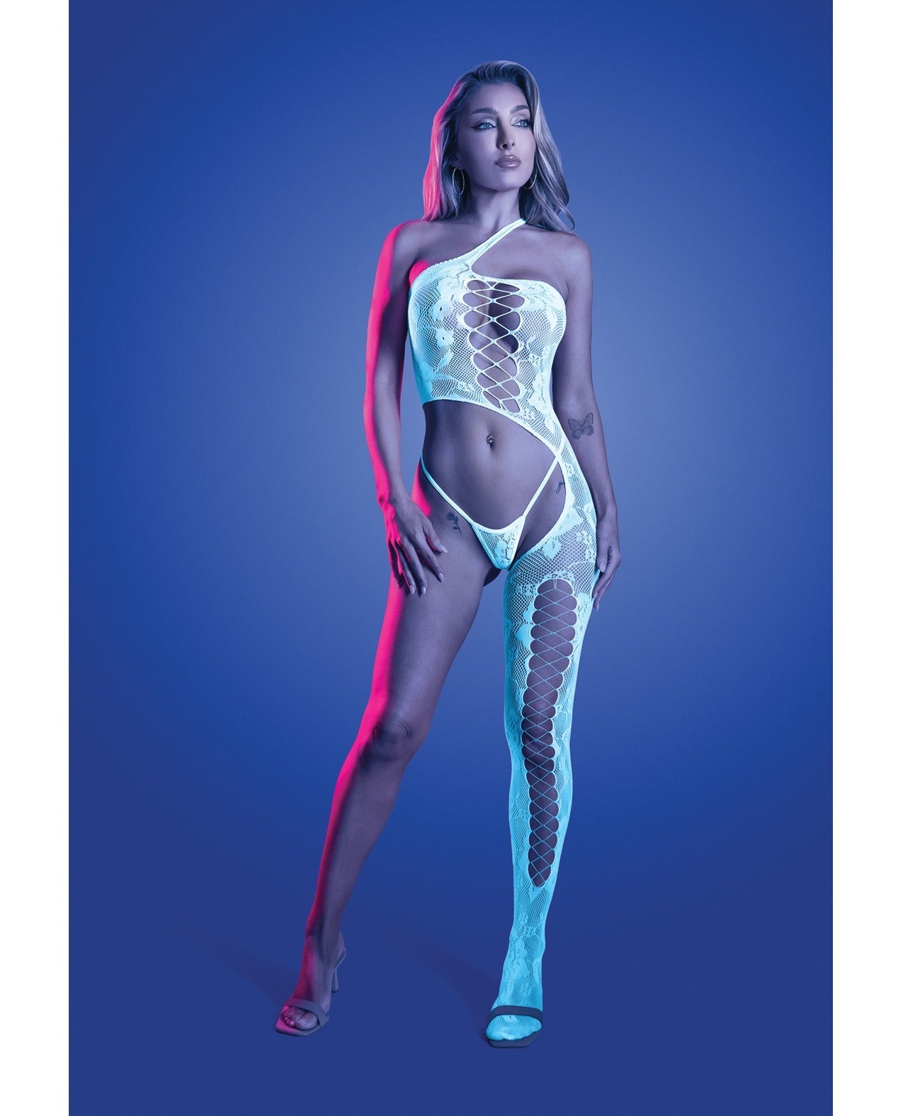 A model poses in a sheer, one-shoulder white bodysuit with a lace-up front and matching fishnet stockings against a blue studio background with pink neon lighting.