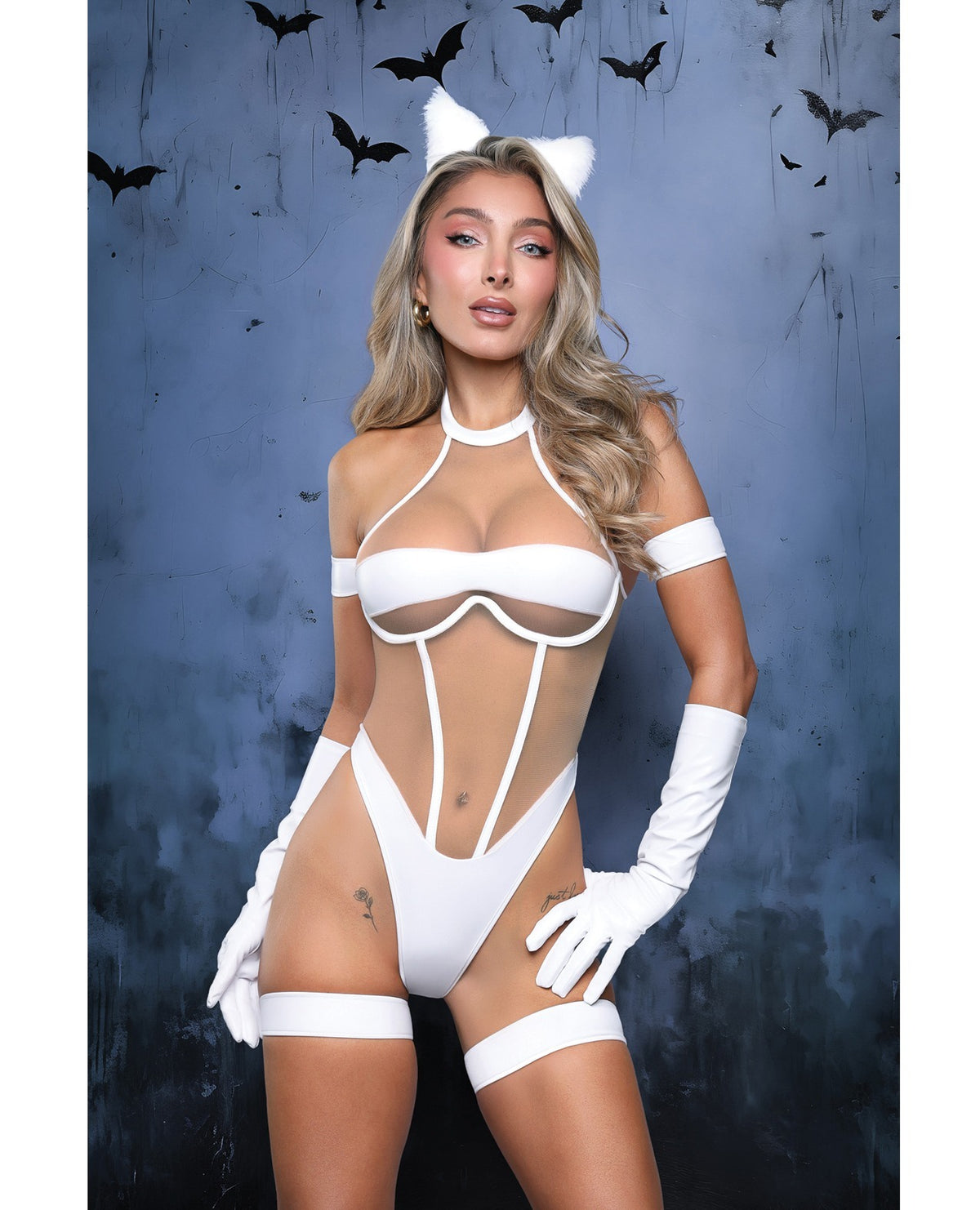A woman modeling a white strappy catgirl-style bodysuit with matching white gloves, thigh bands, and white cat ears against a dark blue textured background with flying bat silhouettes.