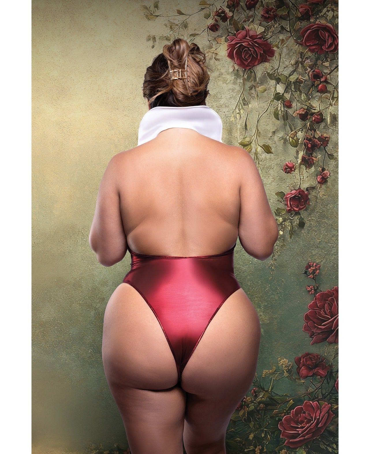 Rear view of a woman wearing a shiny deep red satin thong with a white towel wrapped around her neck, standing against a vintage-style floral wallpaper background with red roses.