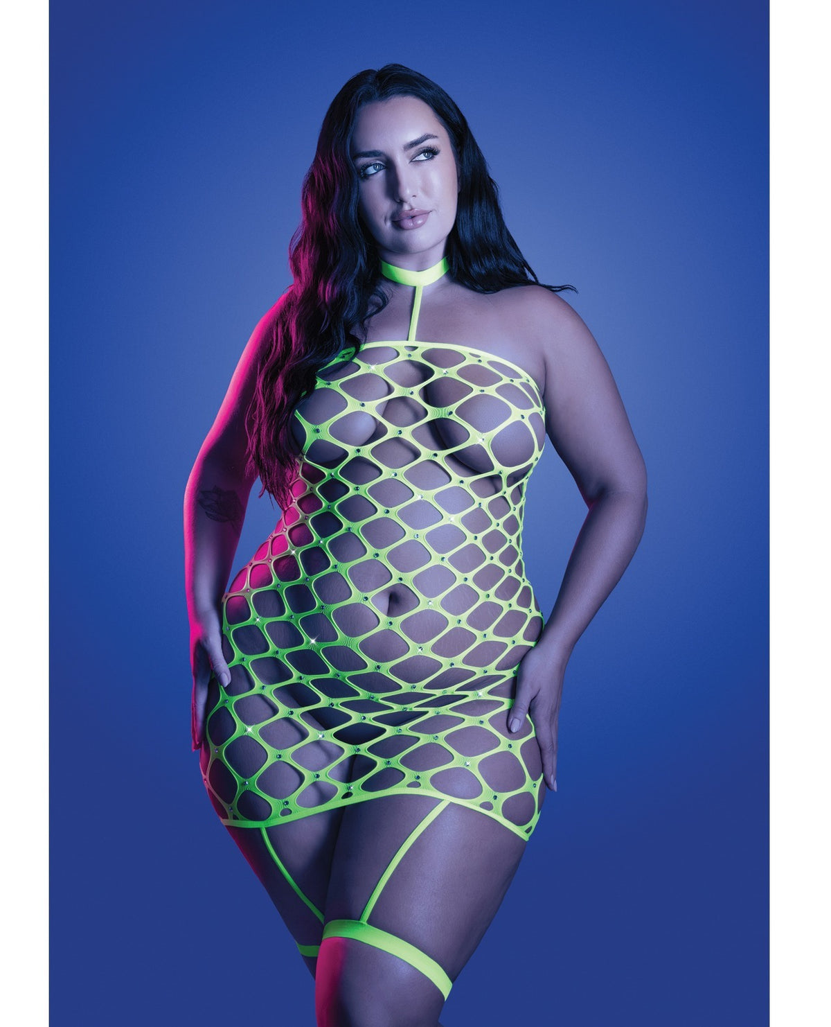 A woman modeling a neon green fishnet halter mini dress against a blue studio background.